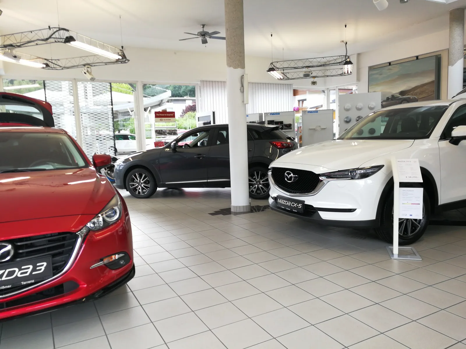 Schauraum mit rotem Mazda 3, dunklem Mazda CX-3 und weißem Mazda CX-5